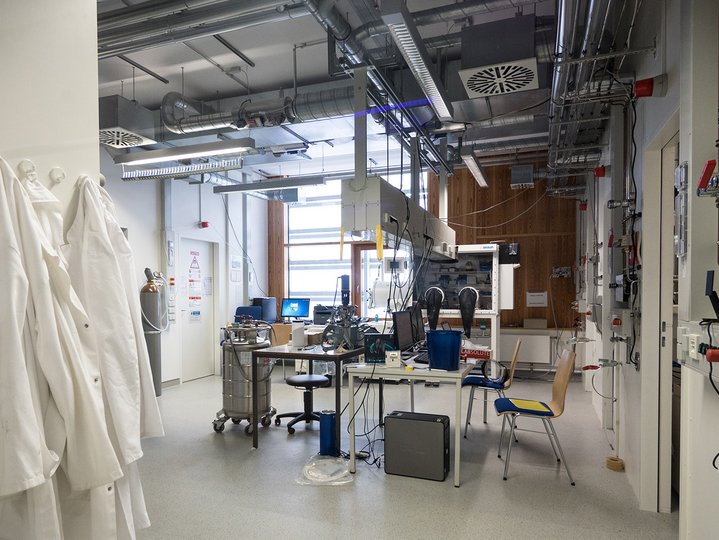 A lab with different mechanical equipments and white lab coat hanged on the side