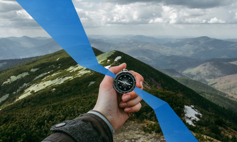 Hand with compass in the mountains