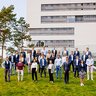Team of the Center for Digital Transformation stands on a hill at the TUM campus Heilbronn in front of a building.