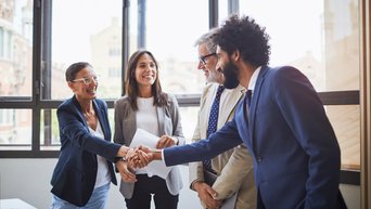 Four business partners shaking hands and smiling 