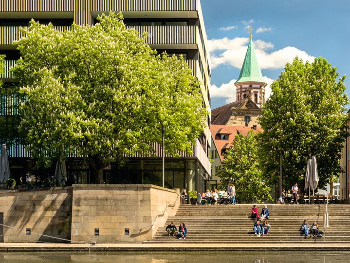 View of the Marer House in Heilbronn with people sitting on the stairs in front of the building.