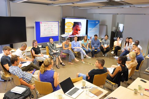 Group of diverse international summer school 2022 students sitting in a circle.