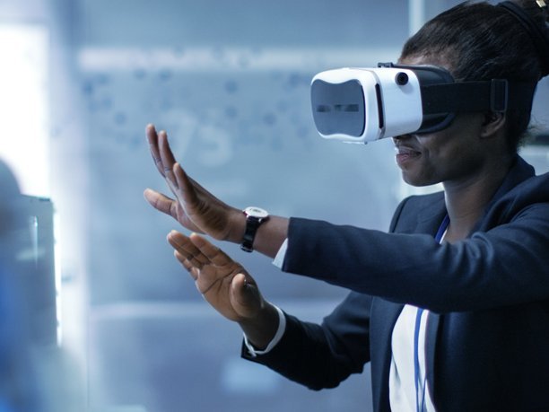 African-American female Virtual Reality Developer wearing VR Headset and creates content. She's alone in a modern research center.