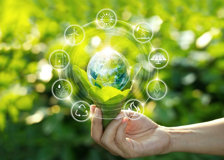 Hand holding light bulb against nature on green leaves with icons energy sources for renewable, sustainable development.