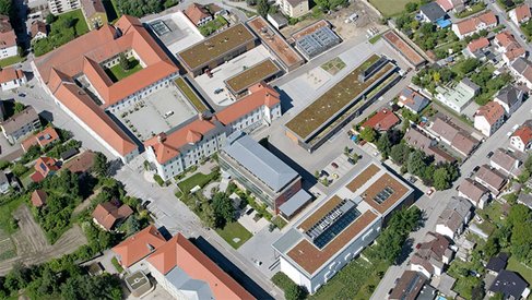 A drone shot taken during the day that has campus and surrounding building 