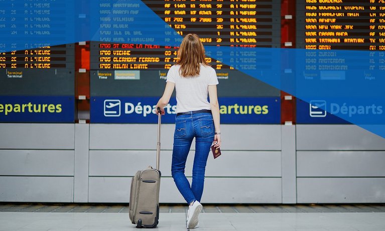 Female student in international airport looking on the departure display