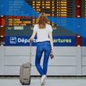 Female student in international airport looking on the departure display