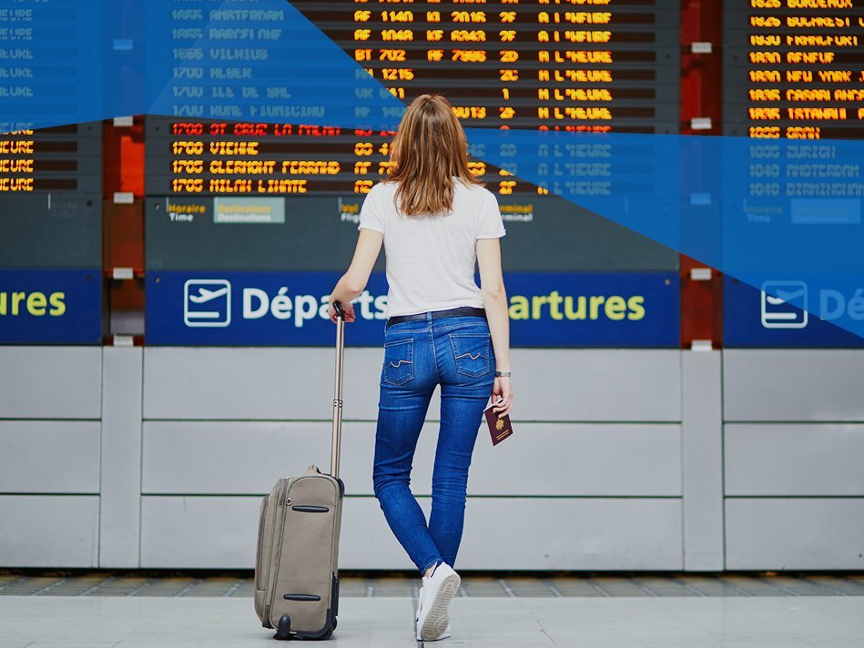 Female student in international airport looking on the departure display