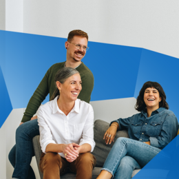 Two women and a man sitting on a couch and laughing.