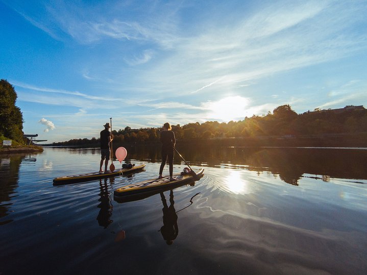 Two people on stand up paddles on the Neckar river. 