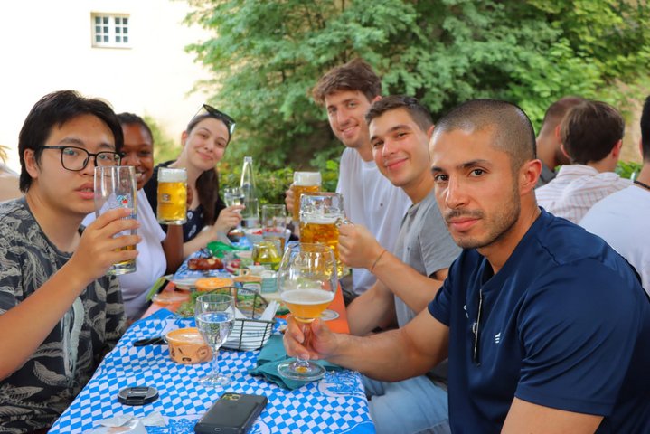 Diverse students of the international summer school 2022 sitting in a bavarian beergarden drinking beer.
