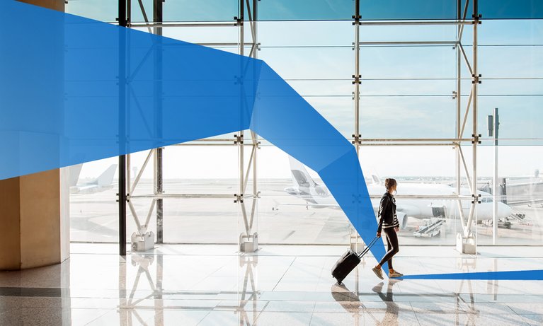 View on the aiport window with young woman walking with suitcase at the departure hall of the airport. 