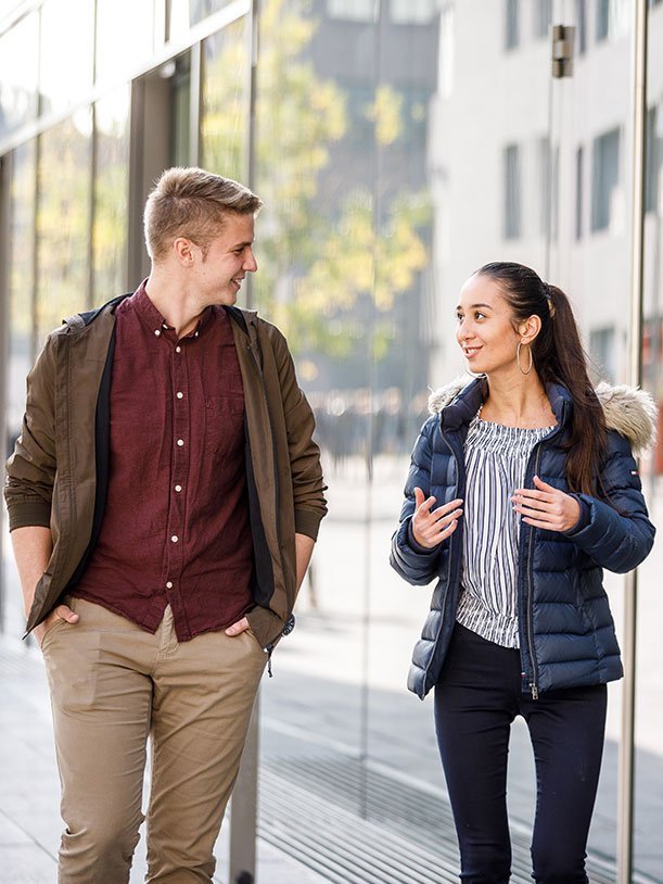 Male and female student talking while walking together.