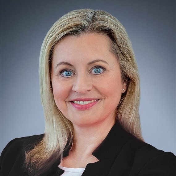Headshot of Katharina Beumelburg, a middle aged woman smiling on a gray background