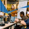 Young woman who is the leader of the project speaking to her colleagues standing near the white board. Diverse team wearing virtual reality glasses in office sitting at the table in an entrepreneurial and innovative enviroment.