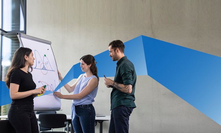 Two female and one male student working together on a flipchart