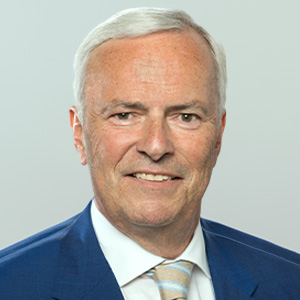 Headshot of Andreas Biagosch, a midle-aged man in a suit on a simple light gray background.