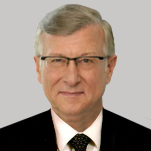 Headshot of Edward Krubasik, a midle-aged man in a suit on a simple light gray background.