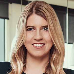 Headshot of Maria Sievert, a young woman smiling at the camera, standing in a room.