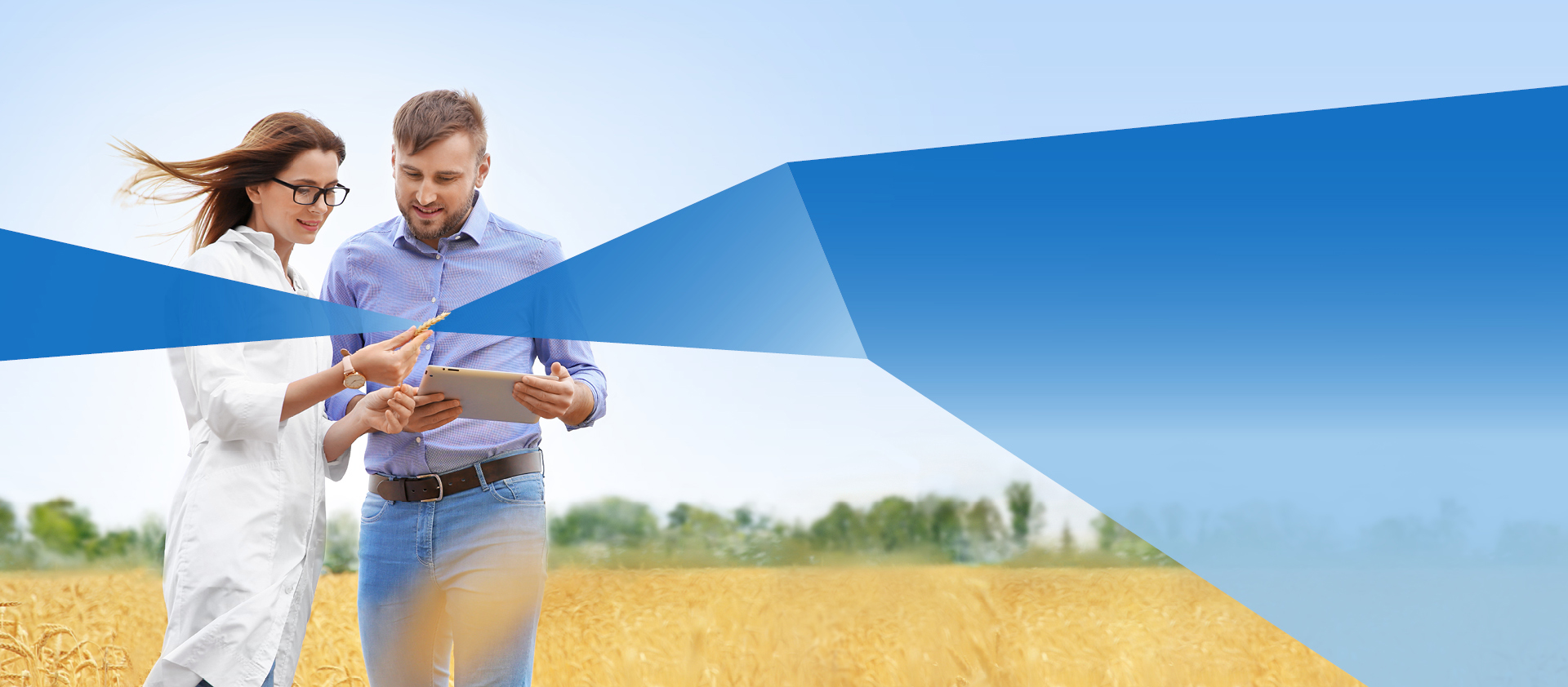 One male and female student in a grain field with tablet