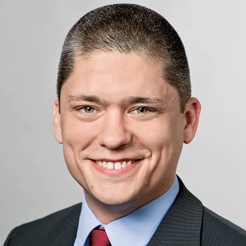 Headshot of Prof. Dr .Oliver Alexy, a middle aged man smiling on a simple light gray background.